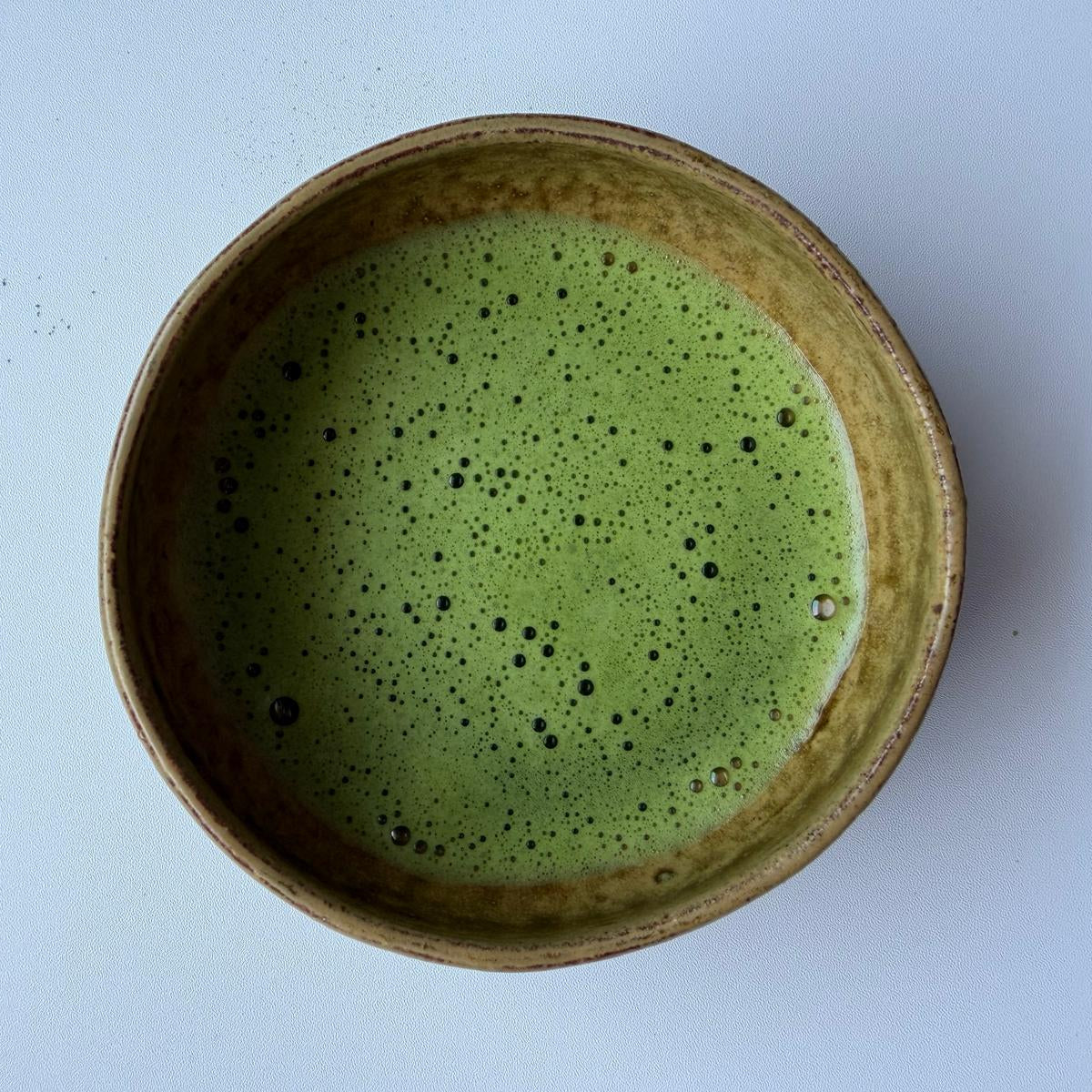 Ceramic bowl with matcha on a light blue background