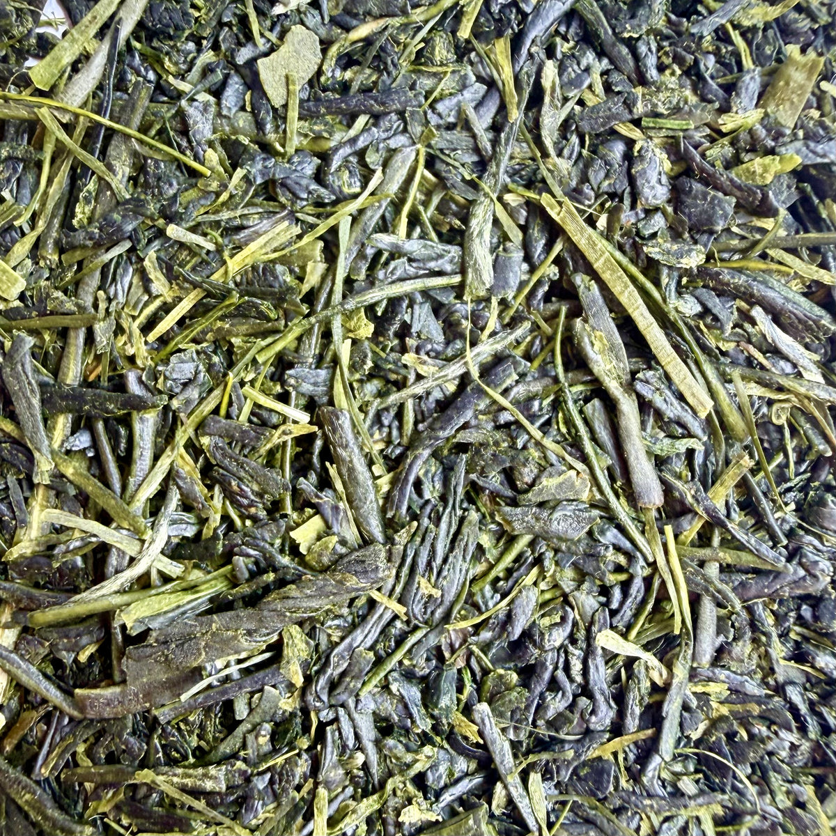 Close-up of loose-leaf tea leaves, showing dark green to olive green rolled leaves