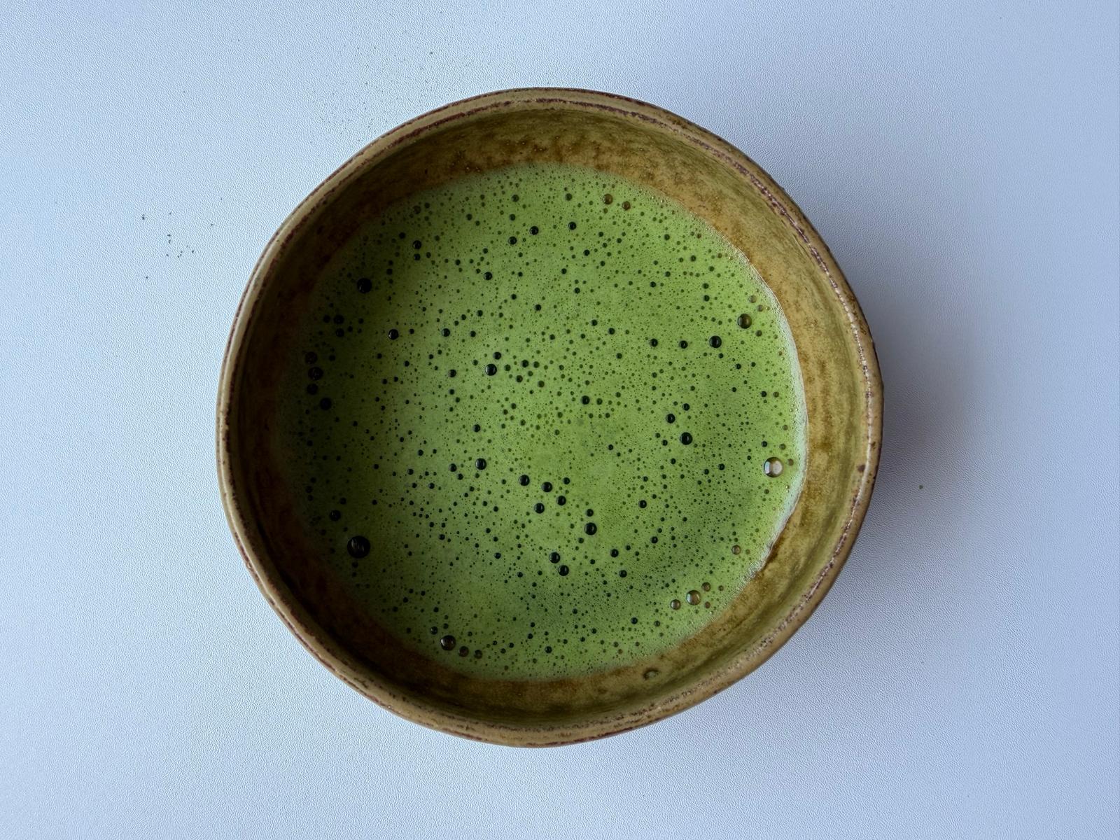 Ceramic bowl with green beverage on a light blue background